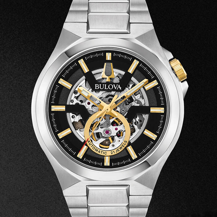 Relógio metálico cinza com detalhes dourados da coleção Maquina de relógios Bulova, símbolo da união perfeita entre estética e mecânica.